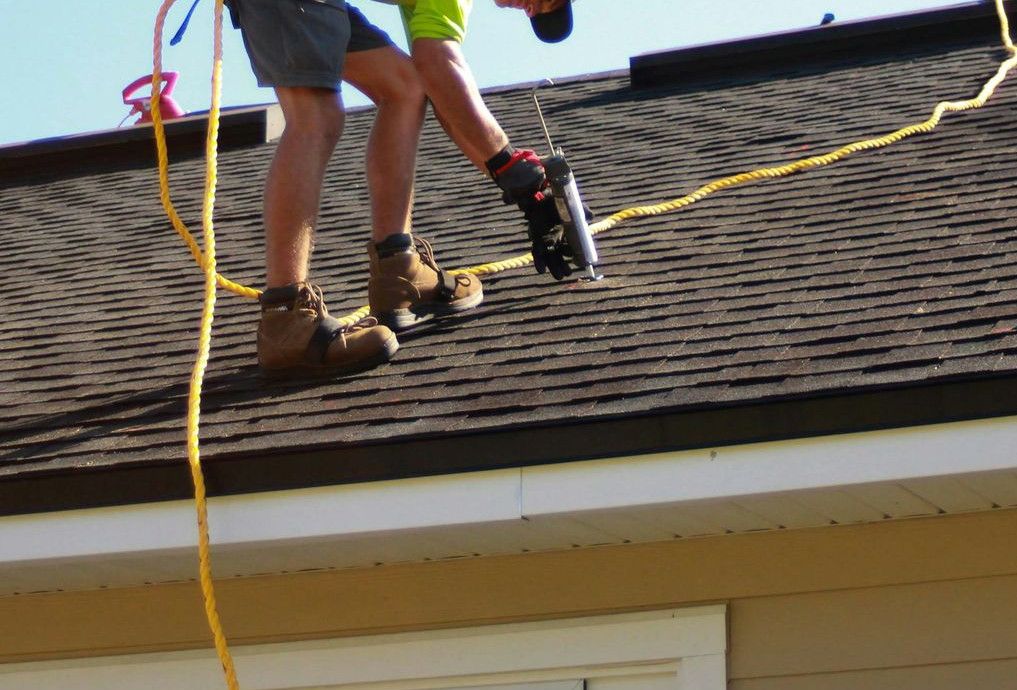 a man working on a roof with a power drill